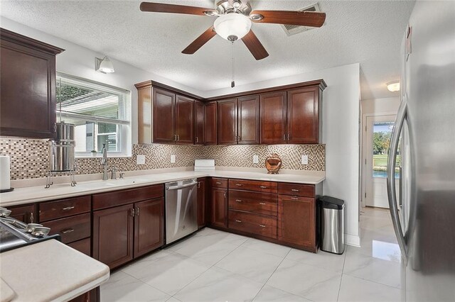 kitchen with a wealth of natural light, decorative backsplash, sink, and stainless steel appliances