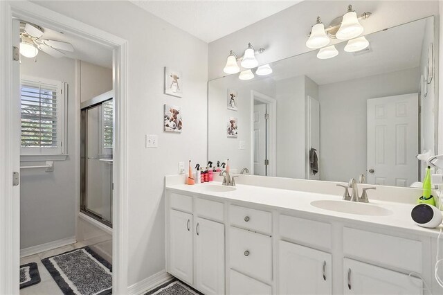 bathroom featuring combined bath / shower with glass door, vanity, and ceiling fan