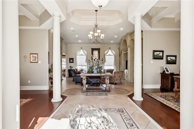 tiled foyer entrance featuring ornate columns, ornamental molding, and a notable chandelier