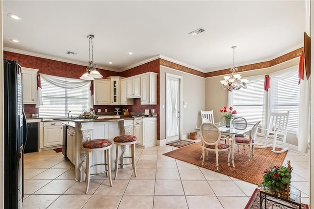 kitchen with decorative light fixtures, a kitchen island, black fridge, and an inviting chandelier