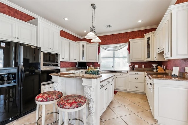 kitchen with a center island, stainless steel microwave, black refrigerator with ice dispenser, hanging light fixtures, and white cabinetry