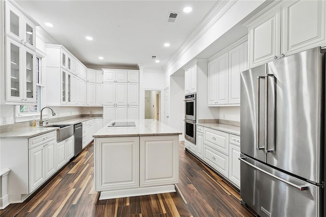 kitchen featuring appliances with stainless steel finishes, dark hardwood / wood-style flooring, sink, a center island, and white cabinetry