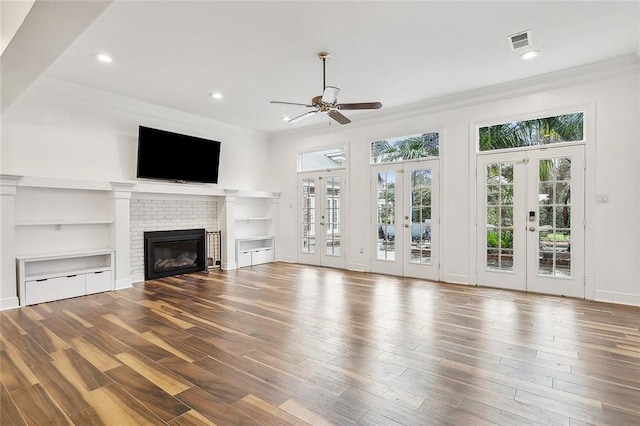 unfurnished living room featuring ceiling fan, wood-type flooring, a fireplace, and french doors