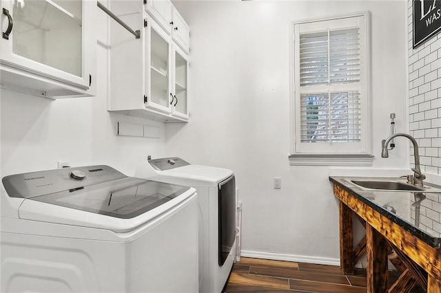 clothes washing area featuring washer and clothes dryer, dark hardwood / wood-style floors, cabinets, and sink