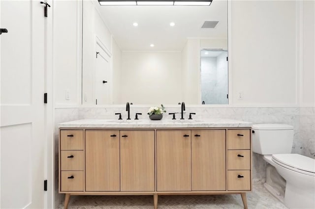 bathroom featuring vanity, toilet, and tile walls