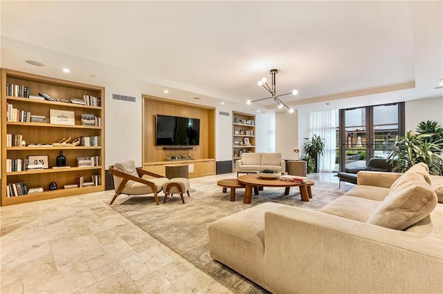 living room featuring built in features, french doors, and an inviting chandelier