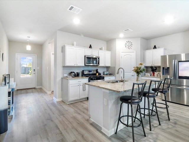 24440 Dawson Ct, Ponchatoula, LA 70454 - kitchen featuring stainless steel appliances, a sink, a breakfast bar area, white cabinetry, and recessed lighting