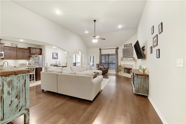 living room featuring ceiling fan, dark hardwood / wood-style flooring, high vaulted ceiling, and sink