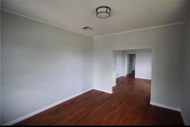 spare room with ornamental molding and dark wood-type flooring