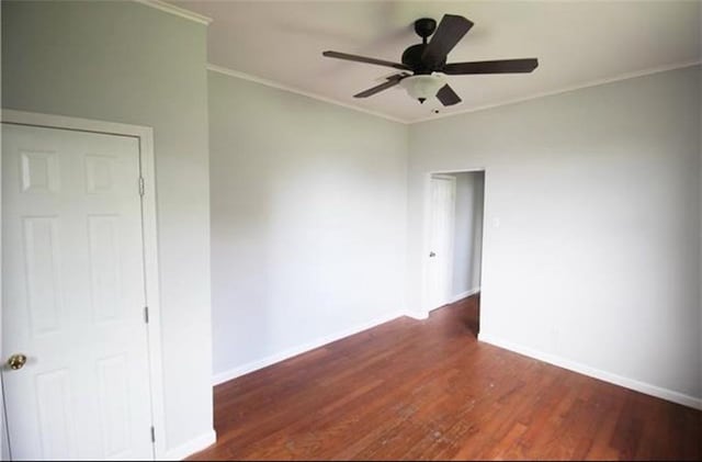 empty room with ceiling fan, dark wood-type flooring, and ornamental molding