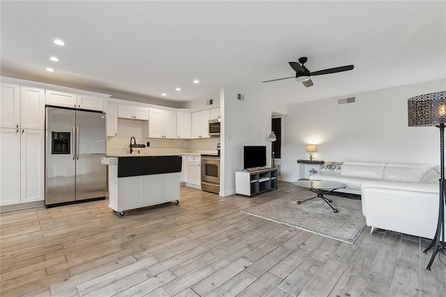 kitchen featuring appliances with stainless steel finishes, sink, white cabinets, a center island, and ceiling fan