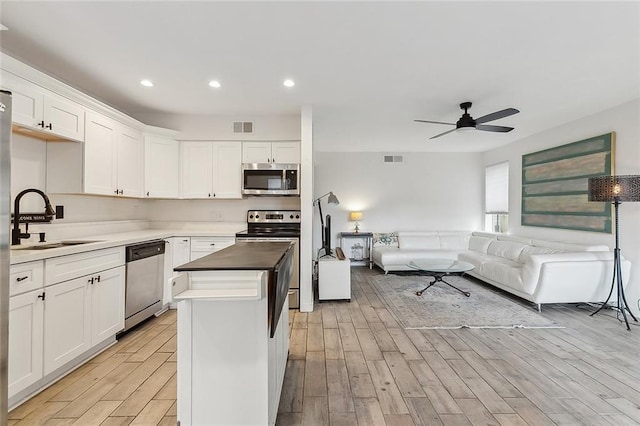 kitchen featuring a kitchen island, white cabinetry, sink, ceiling fan, and stainless steel appliances