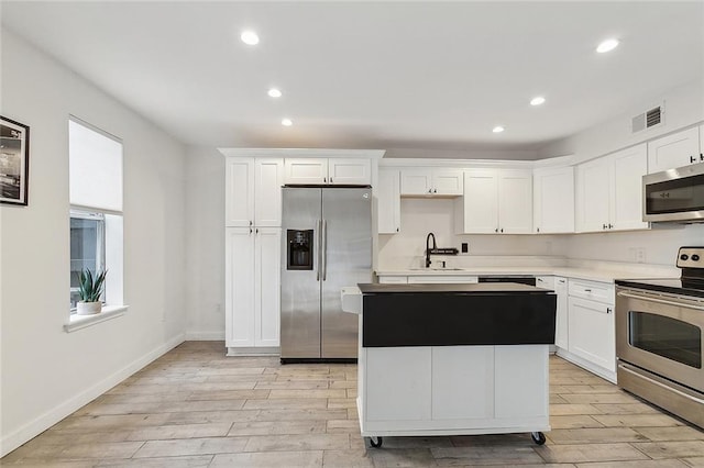 kitchen featuring sink, a center island, white cabinets, and appliances with stainless steel finishes