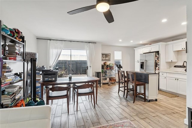 dining area featuring ceiling fan, sink, and light wood-type flooring