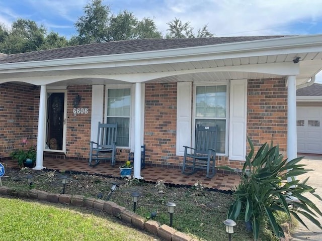 view of exterior entry featuring a garage and covered porch