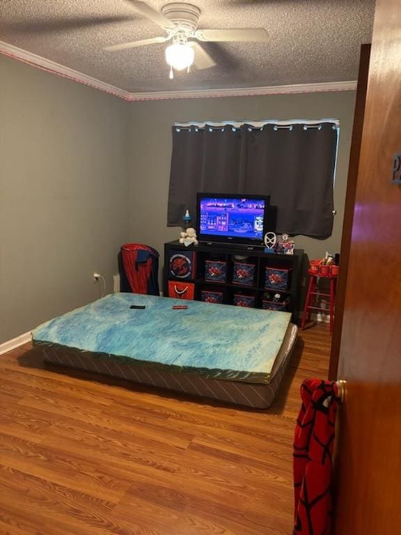 bedroom featuring a textured ceiling, hardwood / wood-style flooring, ceiling fan, and ornamental molding