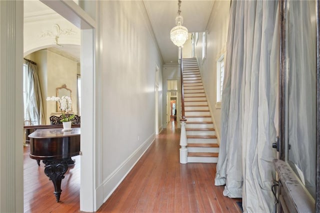 hallway featuring an inviting chandelier, crown molding, and hardwood / wood-style floors