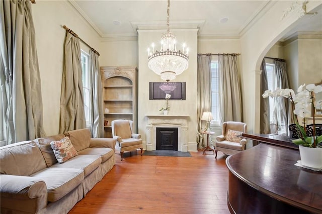 living area with crown molding, wood-type flooring, and a healthy amount of sunlight