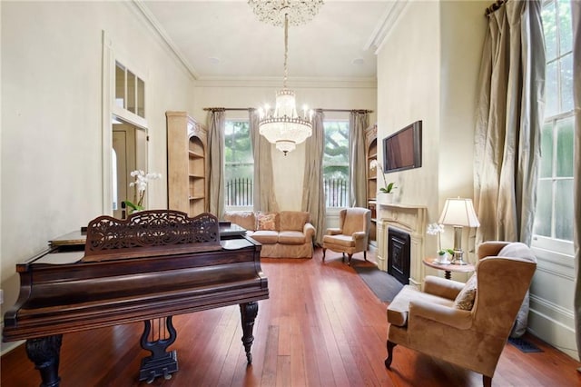 living area featuring crown molding, an inviting chandelier, and hardwood / wood-style floors