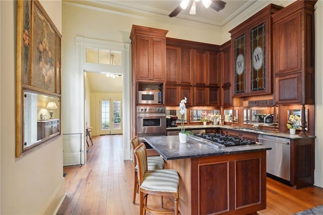 kitchen with a center island, stainless steel appliances, light wood-type flooring, and crown molding