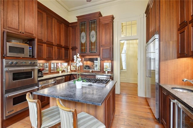 kitchen with dark stone countertops, appliances with stainless steel finishes, a breakfast bar, sink, and a center island