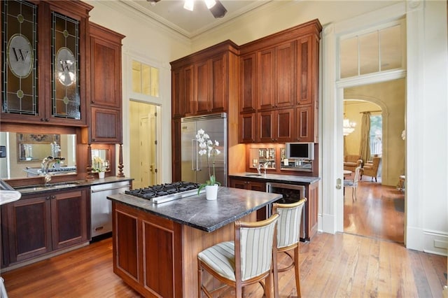 kitchen with appliances with stainless steel finishes, a kitchen island, crown molding, and light hardwood / wood-style floors