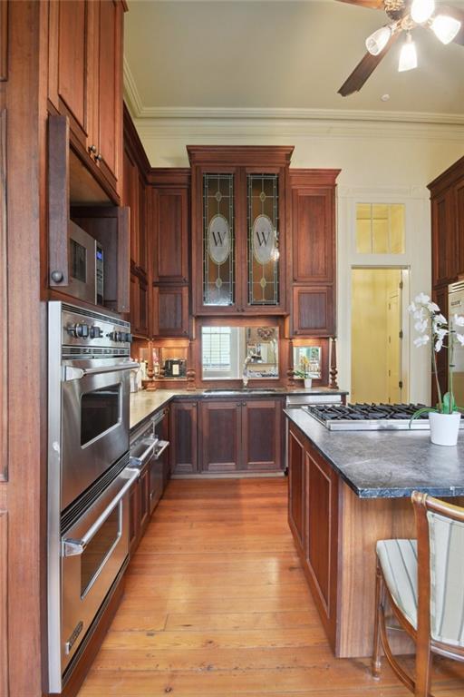 kitchen with appliances with stainless steel finishes, light hardwood / wood-style flooring, a breakfast bar area, and ornamental molding