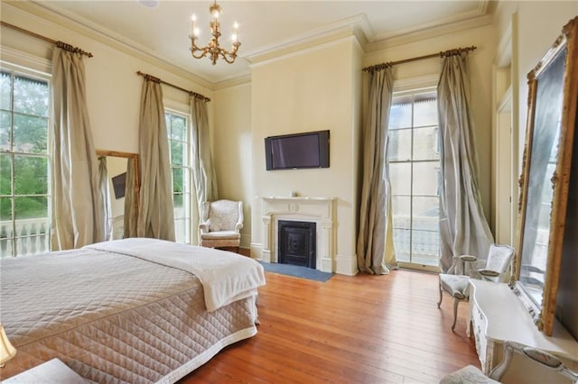 bedroom featuring hardwood / wood-style floors, an inviting chandelier, crown molding, and access to outside