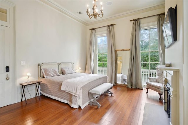 bedroom featuring ornamental molding, an inviting chandelier, and hardwood / wood-style floors