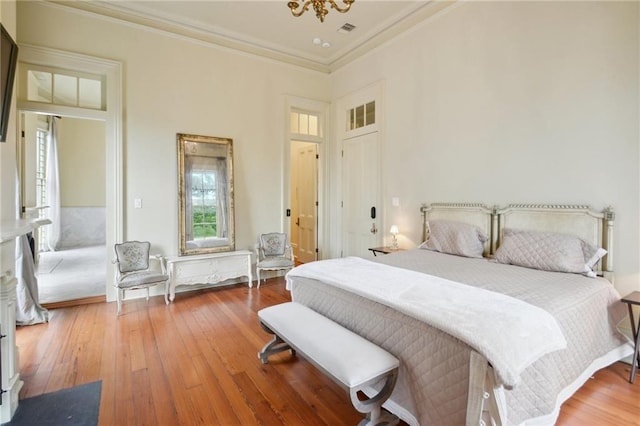 bedroom with a chandelier, crown molding, and hardwood / wood-style floors