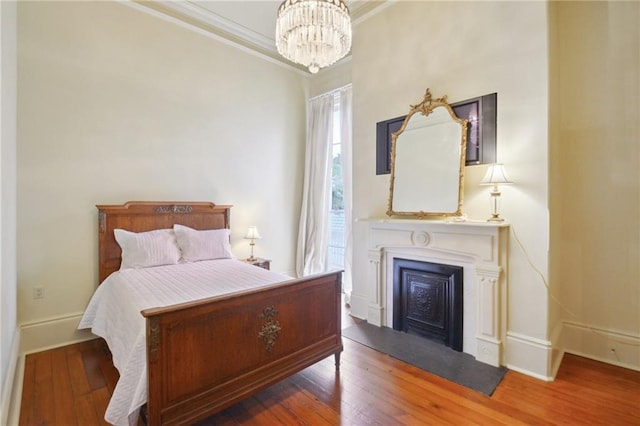 bedroom featuring ornamental molding, hardwood / wood-style floors, and a chandelier