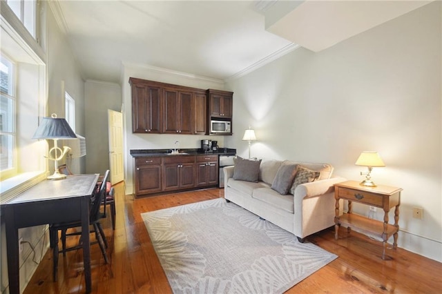 living room with ornamental molding, sink, and wood-type flooring