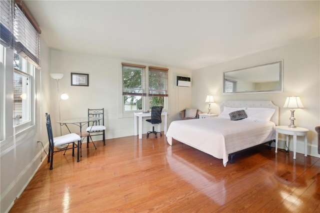 bedroom featuring a wall unit AC and hardwood / wood-style flooring