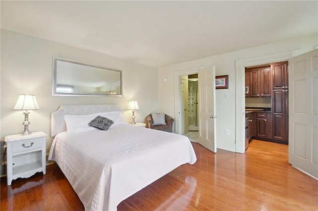 bedroom with ensuite bathroom and light wood-type flooring