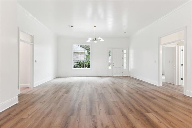 unfurnished living room featuring an inviting chandelier, ornamental molding, and light wood-type flooring