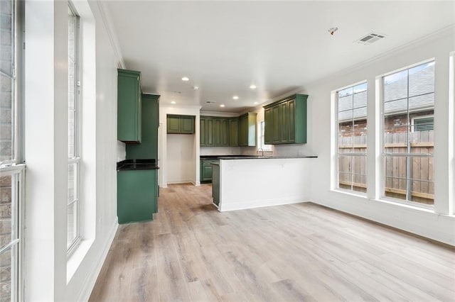 kitchen with green cabinetry, crown molding, and light hardwood / wood-style flooring