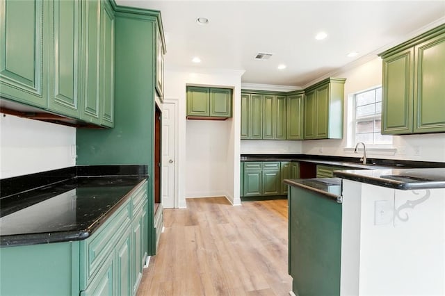 kitchen featuring sink, light hardwood / wood-style flooring, green cabinetry, ornamental molding, and kitchen peninsula