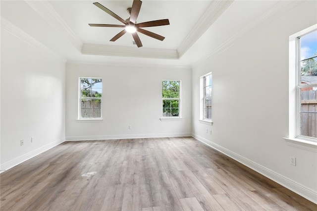 spare room with ceiling fan, crown molding, a tray ceiling, and light hardwood / wood-style flooring