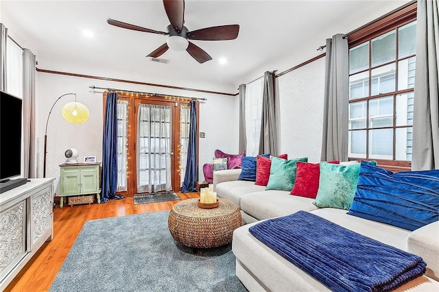 living room with ceiling fan, crown molding, and light wood-type flooring