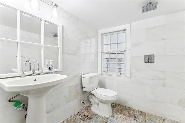 bathroom with tile walls and toilet