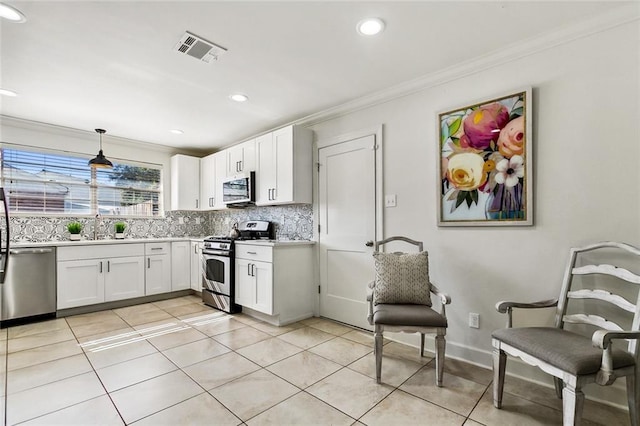 kitchen featuring pendant lighting, white cabinetry, crown molding, and appliances with stainless steel finishes