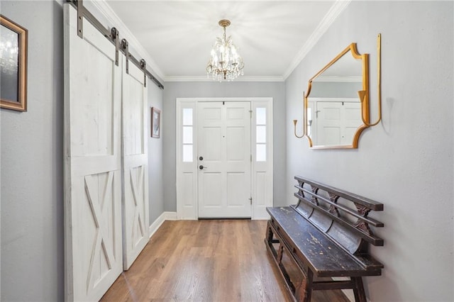 foyer featuring hardwood / wood-style floors, a barn door, an inviting chandelier, and crown molding