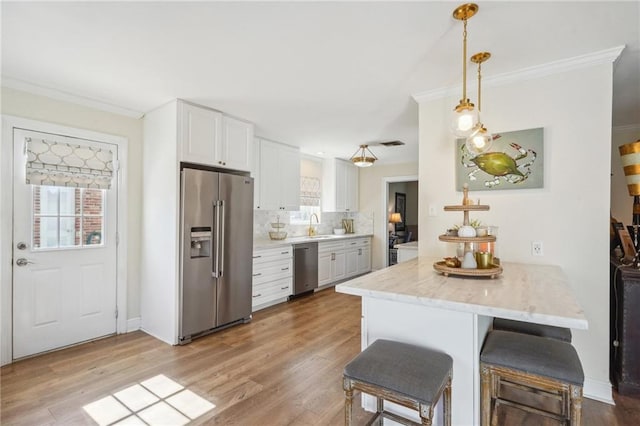 kitchen featuring a breakfast bar, white cabinets, light hardwood / wood-style flooring, kitchen peninsula, and stainless steel appliances