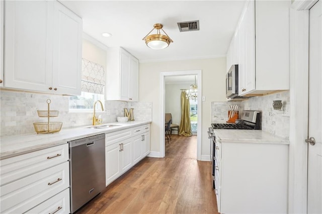 kitchen with light stone countertops, appliances with stainless steel finishes, sink, light hardwood / wood-style flooring, and white cabinetry