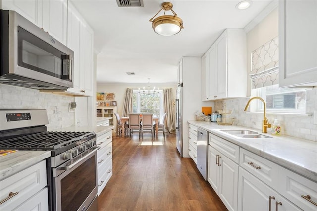 kitchen featuring decorative backsplash, appliances with stainless steel finishes, dark wood-type flooring, sink, and white cabinets