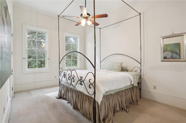 carpeted bedroom featuring ceiling fan and crown molding