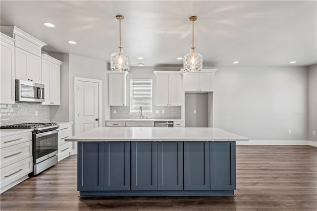 kitchen with pendant lighting, white cabinetry, appliances with stainless steel finishes, and a center island