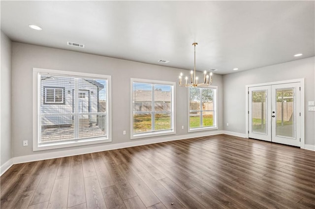 unfurnished dining area featuring french doors, dark hardwood / wood-style flooring, and a chandelier