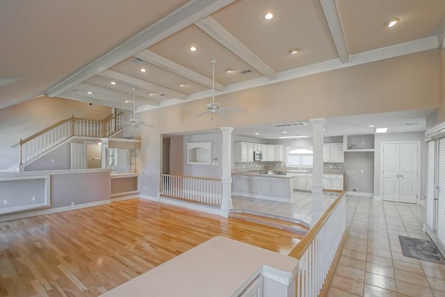 unfurnished living room with ceiling fan, beamed ceiling, and light tile patterned floors