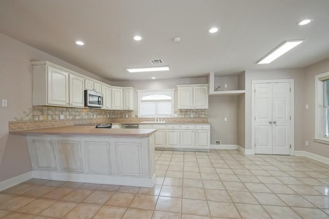 kitchen featuring kitchen peninsula, white cabinetry, and light tile patterned flooring